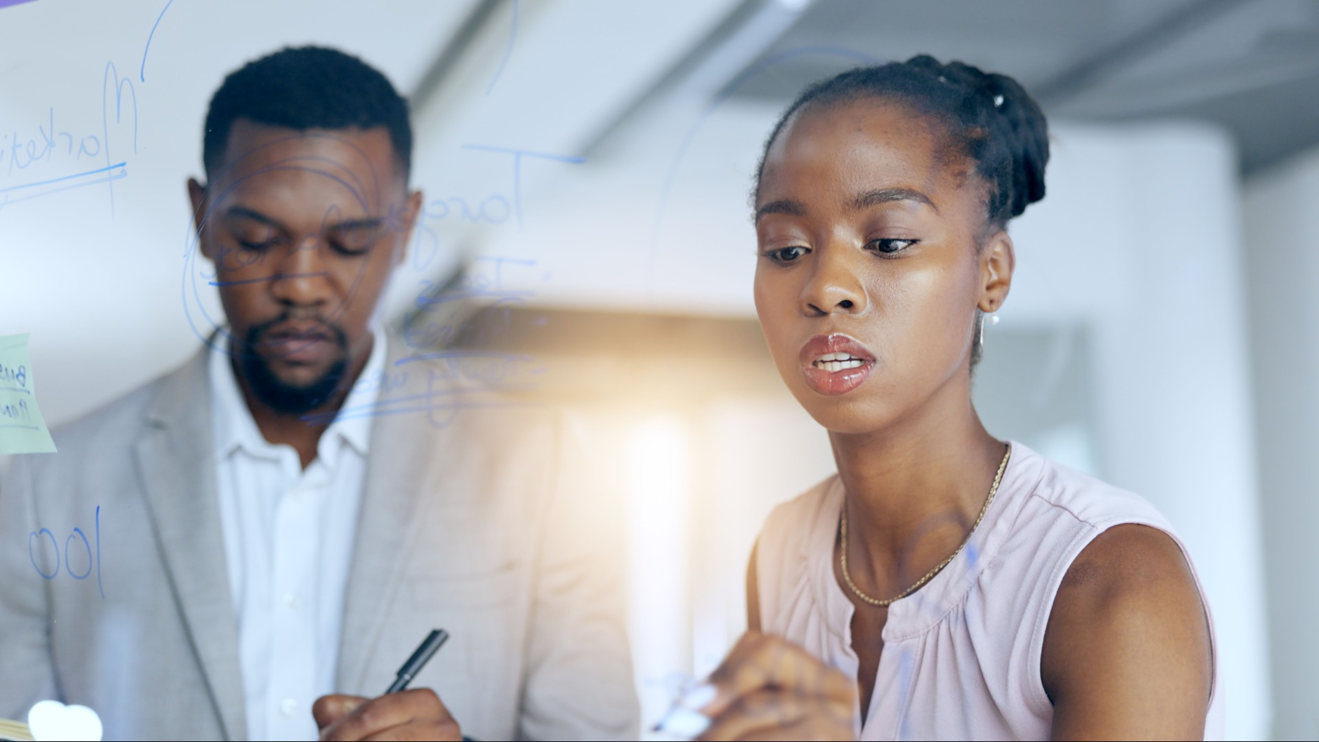 Collaboration, planning and black business people in the office for sticky note or problem solving together. Teamwork, writing and pen with an employee team brainstorming a game plan in the workplace